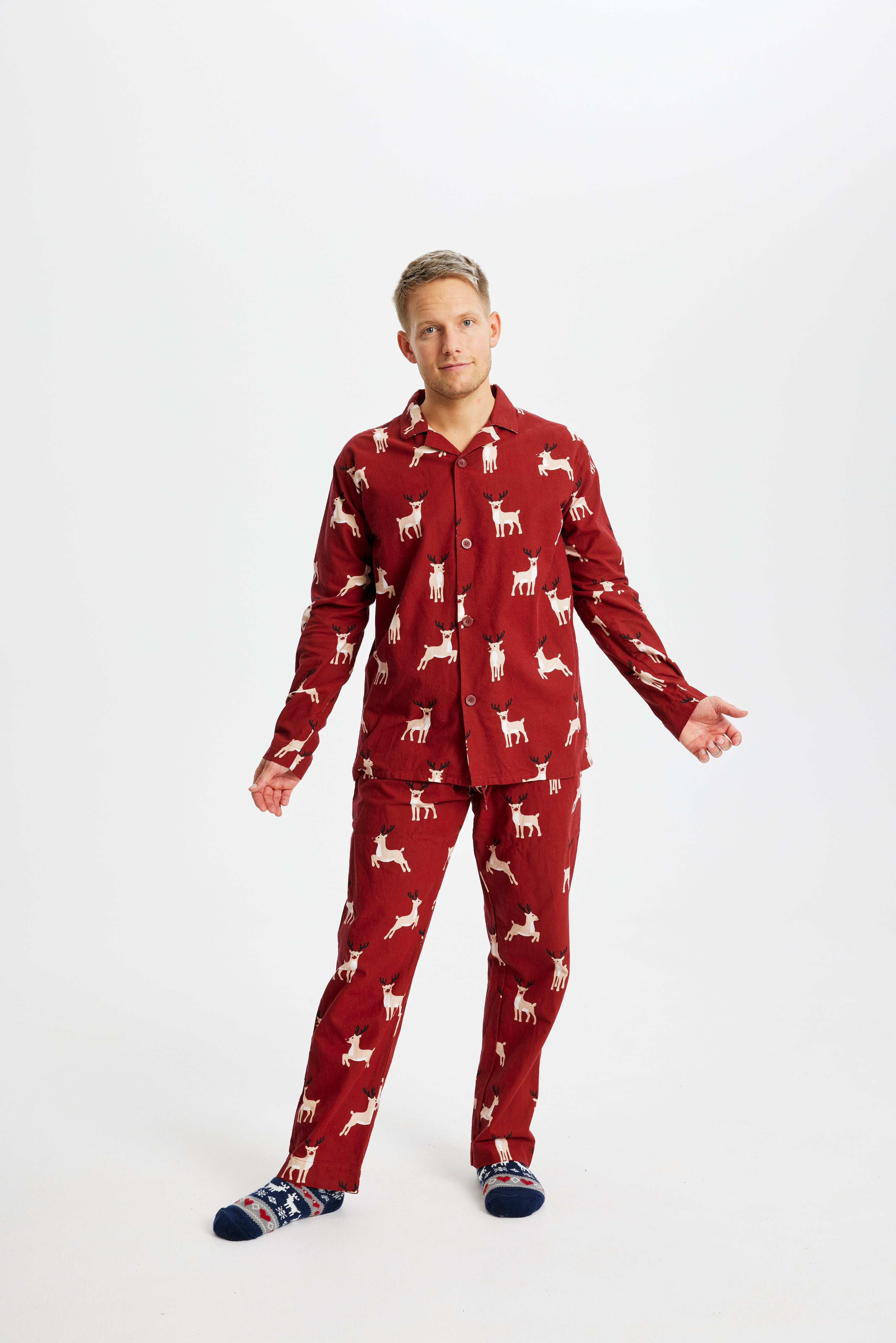 Een man in een rode kerstpyjama met rendieren erop.